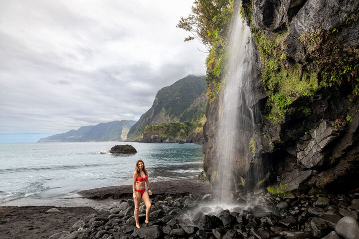 Wasserfall in Madeira, der direkt am Strand in das Meer fließt, umgeben von üppiger Vegetation