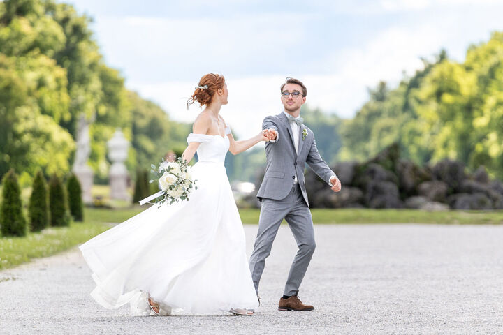 Glückliches Hochzeitspaar im natürlichen Bildlook vor Schloss Nymphenburg bei der Hochzeit