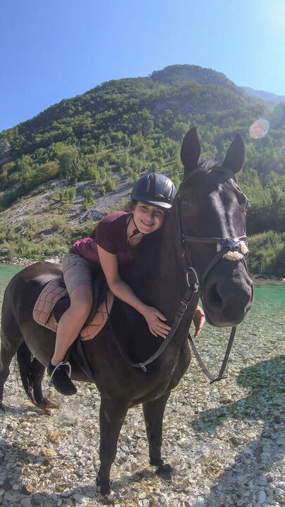 glücklich auf einem Pferd in der Natur, umgeben von einer malerischen Landschaft